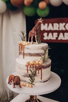 a three tiered cake with an animal figurine on top and decorations around it