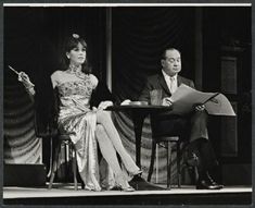 a man and woman sitting at a table in front of a microphone with papers on it