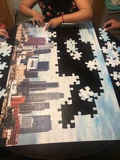 a woman sitting at a table with a large puzzle on it's surface,