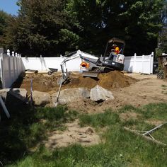 a construction site with a bulldozer digging in the dirt and fence surrounding it