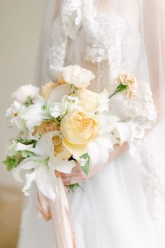 a bridal holding a bouquet of white and yellow flowers