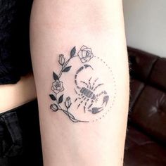 a small tattoo on the arm of a woman with flowers and a scorpion in it