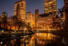 the city is lit up at night and reflecting in the water with its lights on