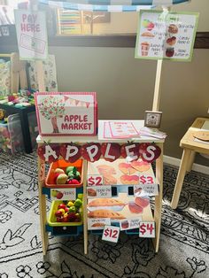 an apple market stand with apples and other fruit on display in front of the sign