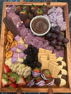 a wooden tray filled with different types of snacks and desserts on top of each other