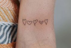 a woman's arm with four small hearts on it