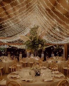 the tables are set up for an event with white linens and lights strung overhead