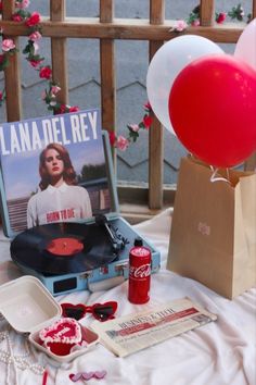 a record player and some red balloons on a table with a sign that reads lana del ray