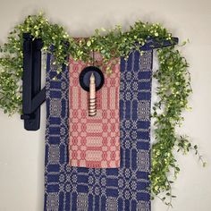 a blue and pink towel hanging on a wall next to a planter with green leaves