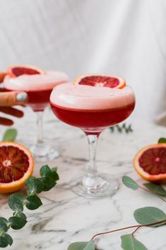 two glasses filled with blood orange margaritas and garnished with greenery