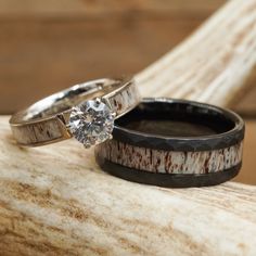 two wedding rings sitting on top of a piece of driftwood next to each other