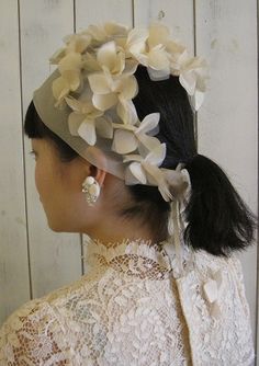 a woman wearing a white hat with flowers on it's head and an earring