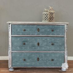 an old dresser has been painted with blue and white paint, as well as a decorative vase on top