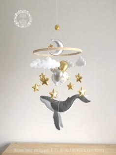 a baby mobile with a whale and stars hanging from it's side on a wooden table