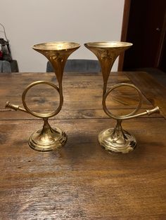 two brass candlesticks sitting on top of a wooden table