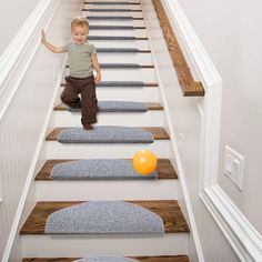 a young boy is standing on the stairs with an orange ball in front of him