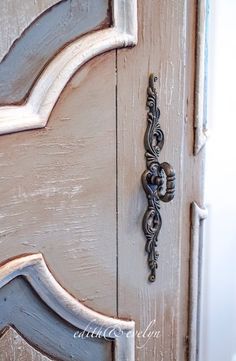 an ornate door handle on the side of a white painted wooden door with metal hardware