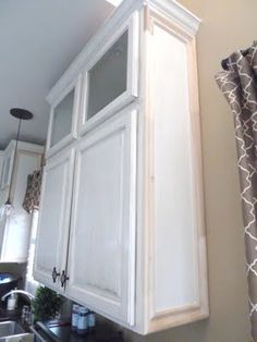 a kitchen with white cupboards and black counter tops next to a window in the wall