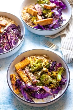 three bowls filled with food on top of a blue tablecloth next to silverware