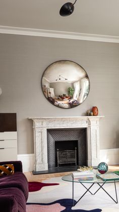 a living room filled with furniture and a fire place under a mirror on the wall