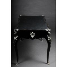 an antique black and white desk with silver trimmings on the top, sitting against a gray background