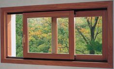 an open window with the view of trees through it's panes in front of a gray wall