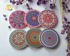 six hand painted coasters sitting on top of a table next to purple flowers and dried lavender