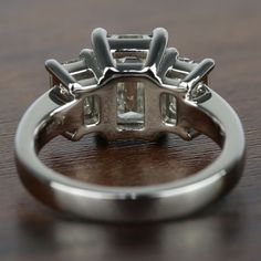 a diamond ring on a wooden table, with the center stone surrounded by smaller stones