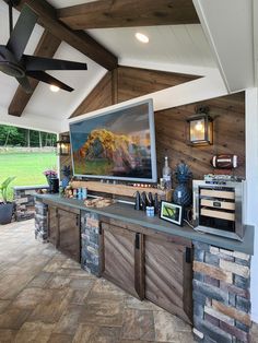 an outdoor bar with televisions on the wall and ceiling fans in the back ground