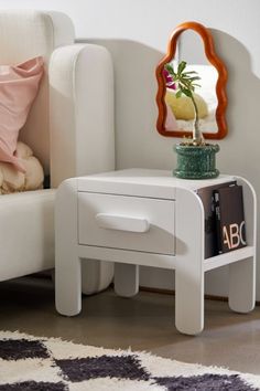 a small white table with a mirror on it next to a couch and chair in a room