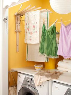 a washer and dryer in a small room with clothes hanging on the line