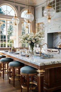 an elegant kitchen with marble counter tops and gold accents, along with blue stools