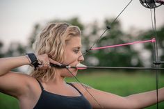 a woman is practicing her archery skills in the field