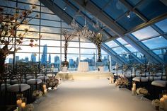 a wedding ceremony setup with candles and flowers on the aisle in front of large windows