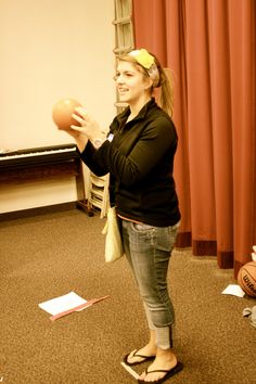 a woman is holding an orange ball in her hand