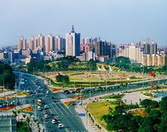 an aerial view of a city with lots of tall buildings and cars driving down the road