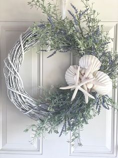 a wreath with sea shells and greenery on the front door