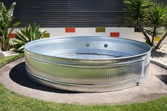 a large metal tub sitting on top of a lush green field next to a palm tree