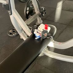 a hello kitty figurine sitting on top of a gym equipment bench in a gym