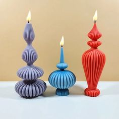 three different colored candles sitting next to each other