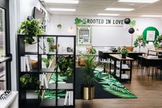 a room with tables, chairs and plants on the wall in it that says rooted in love