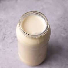 a glass jar filled with milk sitting on top of a gray counter next to a white wall