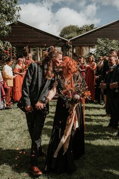 Groom in dark grey three piece suit and burgundy flower patterned tie and bride in embellished black wedding dress holding large orange dried flower bouquet kissing during wedding confetti exit | Katy Jones Photography Coloured Wedding Dress Alternative, Black Dress For Wedding, Edgy Wedding Dress, Dark Grey Suit, Alternative Wedding Inspiration, Orange Drapes, Burnt Orange Bridesmaid Dresses, Edgy Bridal, Backyard Wedding Dresses