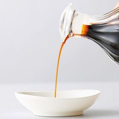 a white bowl filled with liquid being poured into it on top of a white table