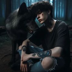 a woman sitting on the ground next to a wolf