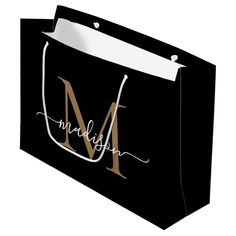 a black shopping bag with the letter m in cursive writing and a white handle