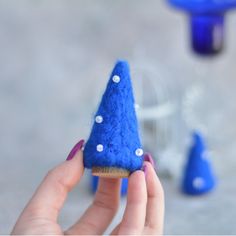 a hand holding a tiny blue cone with white polka dots on it and some other items in the background