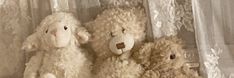 three stuffed animals sitting next to each other on a window sill in front of a curtain