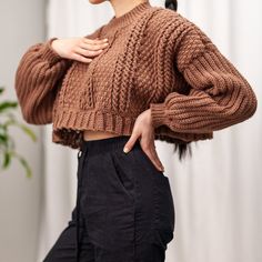 a woman wearing a brown sweater and black pants