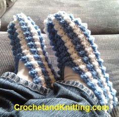 someone's feet wearing blue and white crocheted slippers on a couch